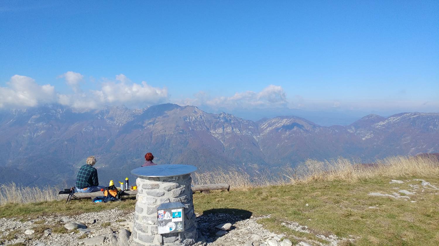 Pohodnika med počitkom na vrhu Porezna s pogledom na okoliške gore